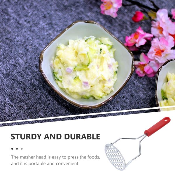 Small bowl of mashed food with a masher on a textured surface with flowers.