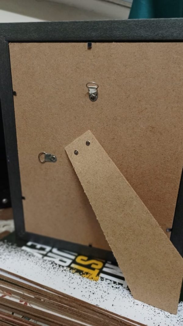 Close-up of a cardboard backing with metal hooks on a textured surface.