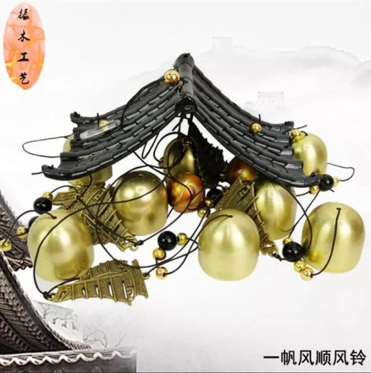 Decorative wind chime with gold balls and black roof-like structure on a white background